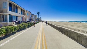 A coastal road with a sidewalk, beach, and beachfront buildings. - Large 5 Bedroom House Beach side in Mission Beach (San Diego)