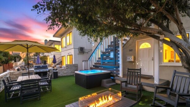 A backyard with a hot tub, barbecue, and outdoor seating area. - Large 5 Bedroom House Beach side in Mission Beach (San Diego)