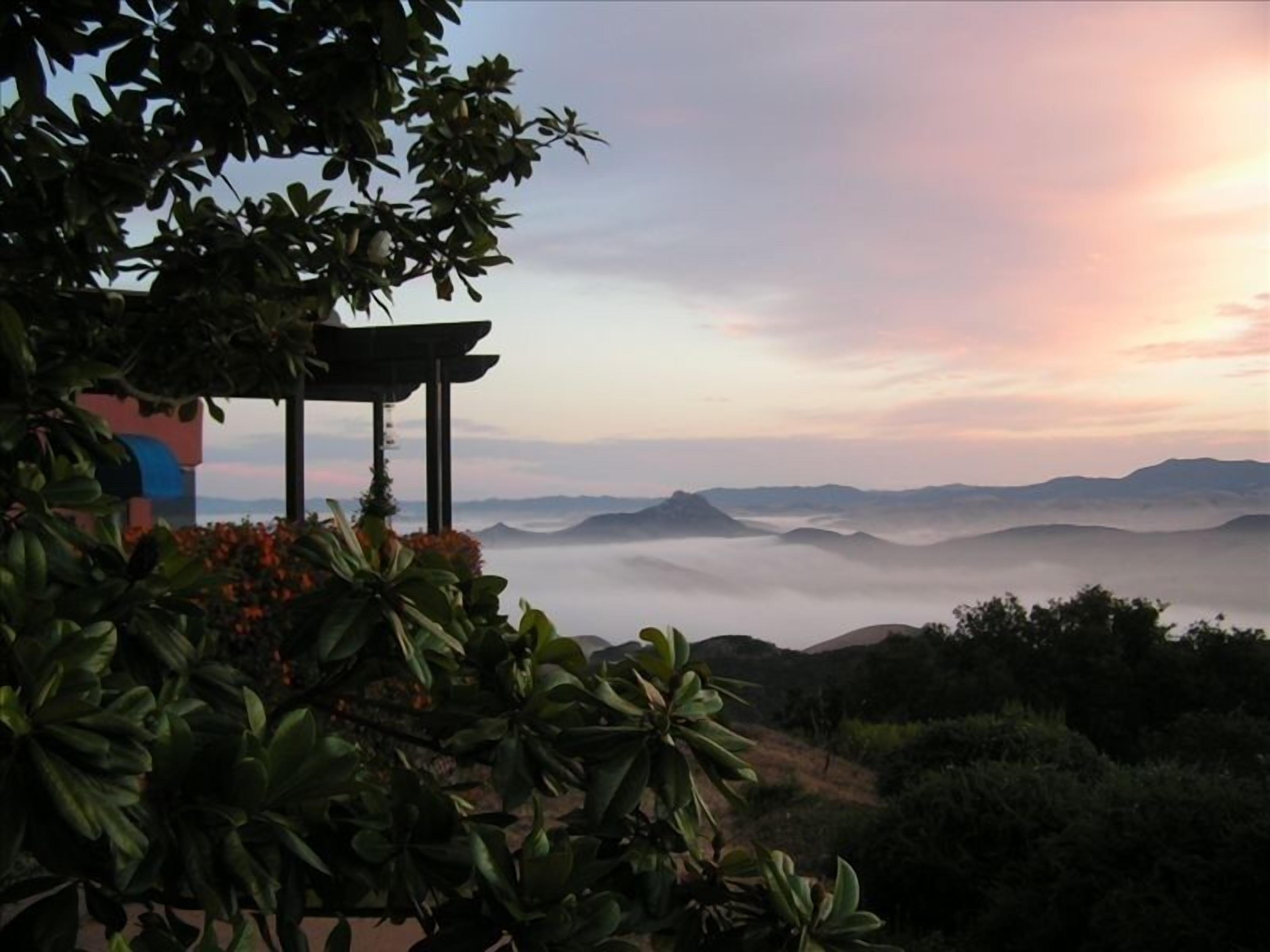 A gazebo with a view of mist-covered mountains and a sunset.