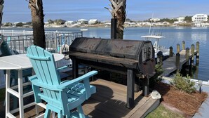 A deck with a grill, turquoise chairs, and a view of the water. - Recently updated!  3 bed 3 bath waterfront condo (Orange Beach)