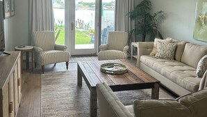 A spacious living room with a large sofa, two striped armchairs, a wooden coffee table, and a ceiling fan. - Recently updated!  3 bed 3 bath waterfront condo (Orange Beach)