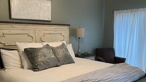 A bedroom with a large bed, a ceiling fan, a nightstand, a lamp, and a chair. - Recently updated!  3 bed 3 bath waterfront condo (Orange Beach)
