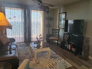 A living room with a sofa, a coffee table, a TV stand, and a ceiling fan.