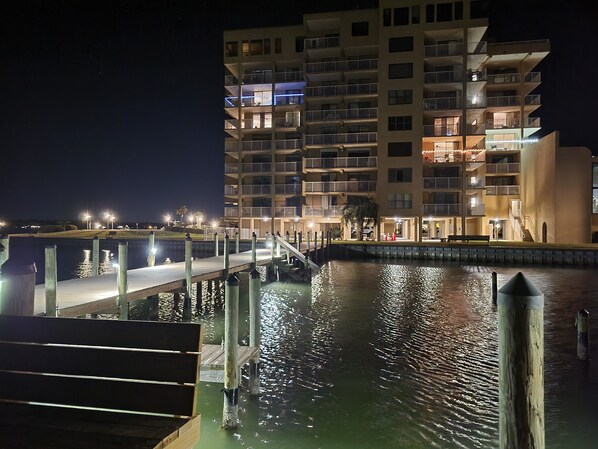 A waterfront hotel with multiple balconies, a dock, and a reflection in the water.