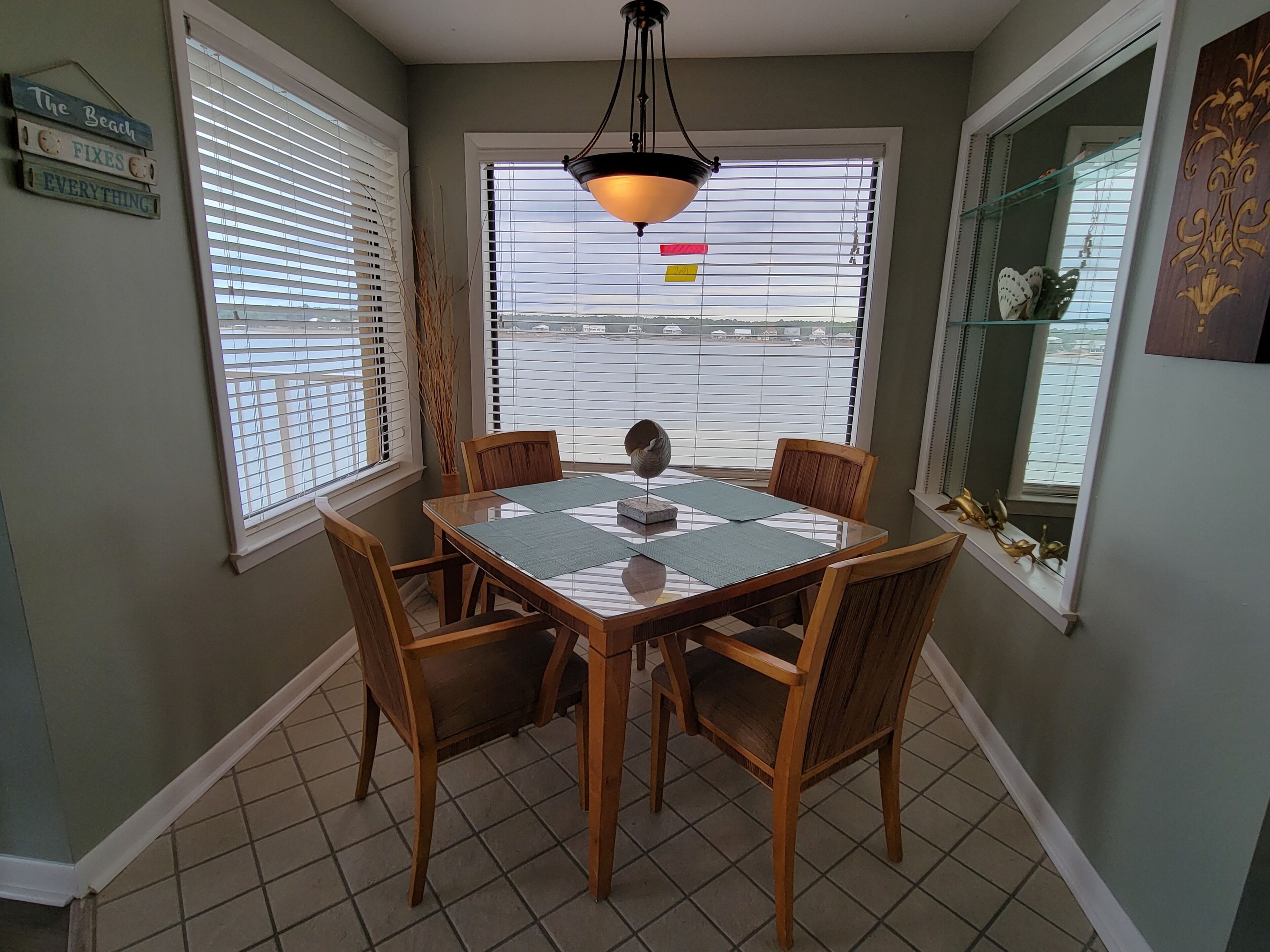 Ein Essbereich mit einem Glastisch, Holzstühlen und Blick zum Himmel durch große Fenster.