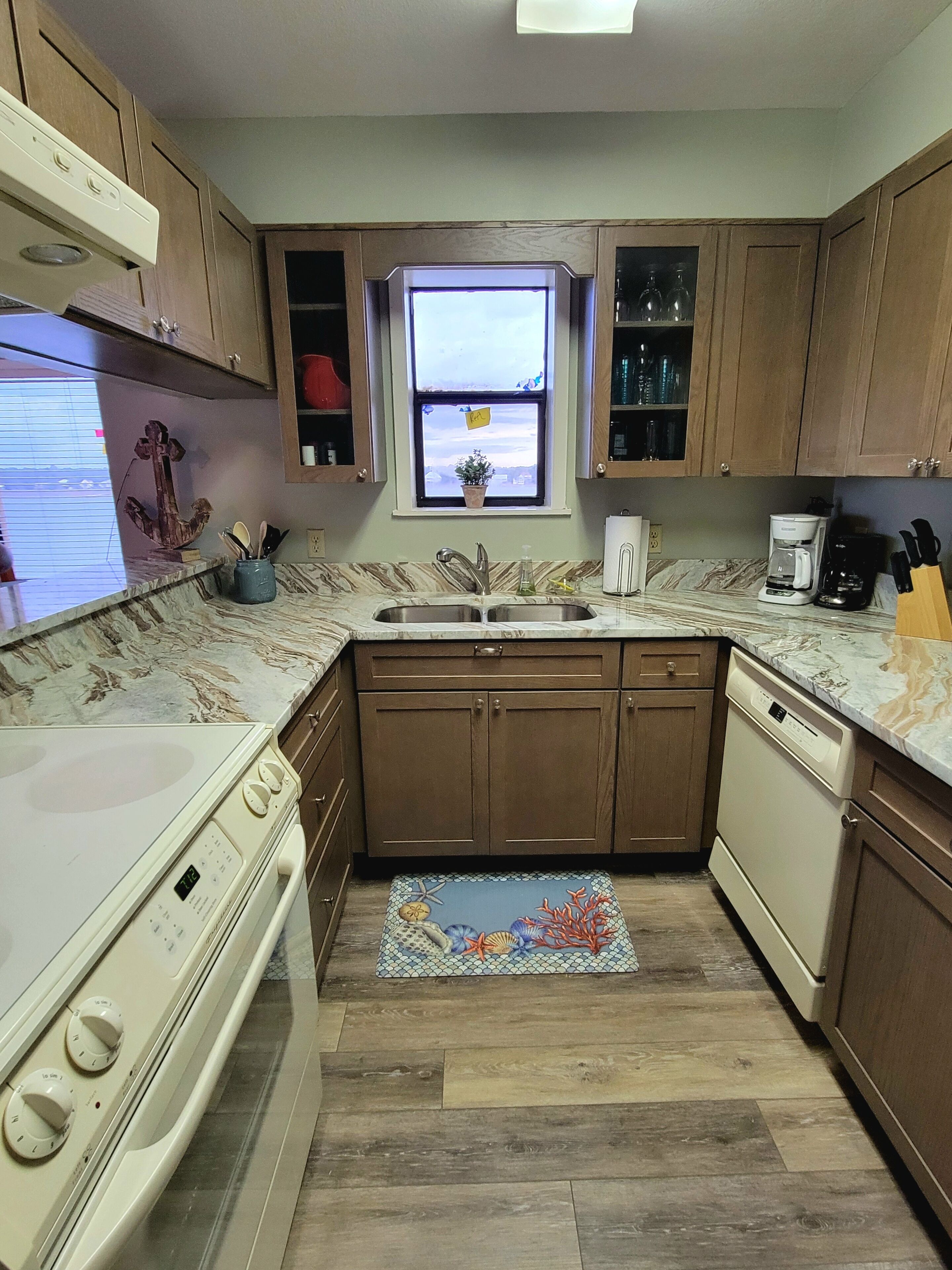 A kitchen with wooden cabinets, a sink, a stove, and a dishwasher.