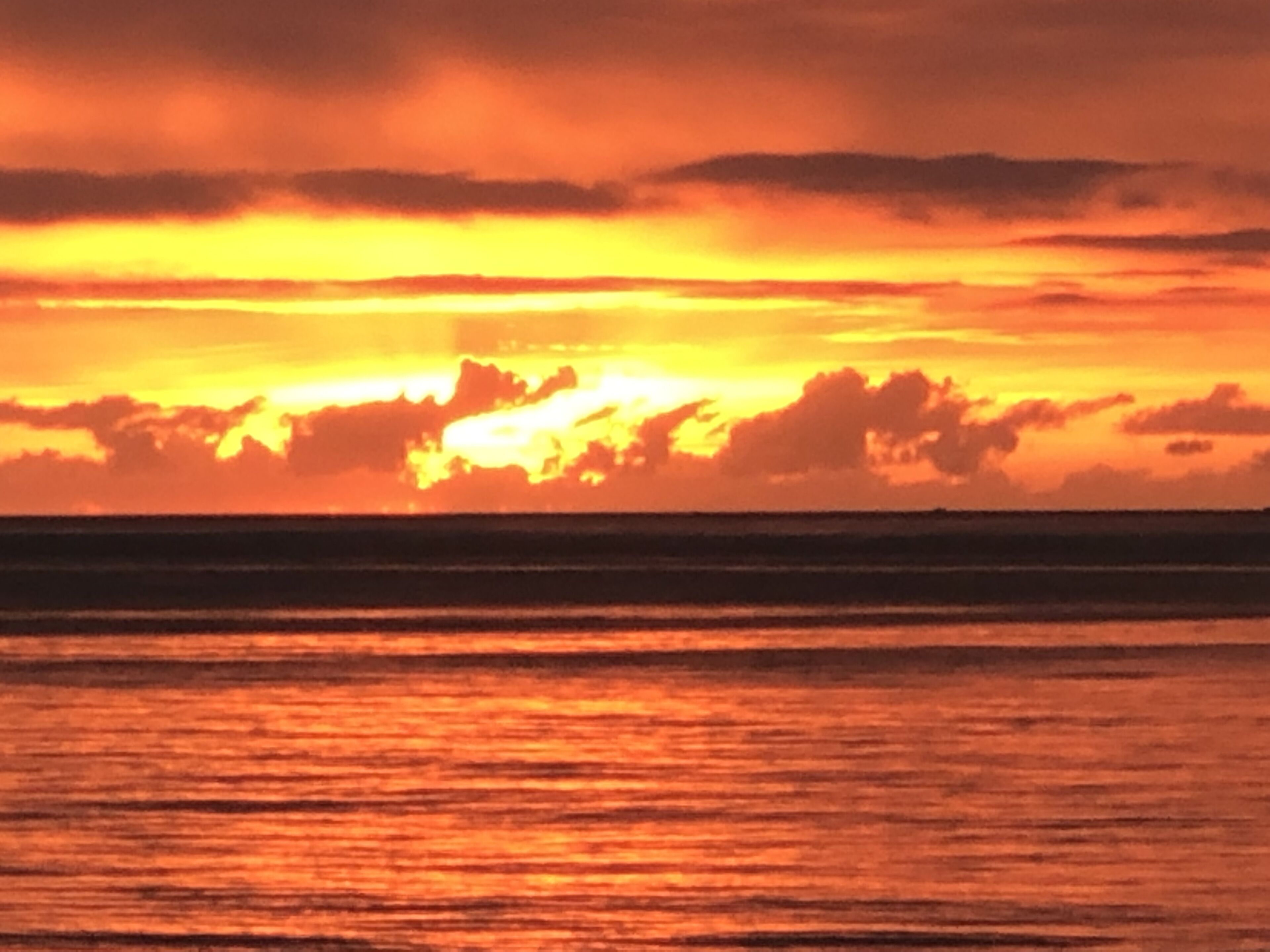 A sunset over the ocean with a clear horizon.