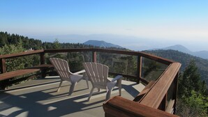 A balcony with two Adirondack chairs overlooking a mountainous landscape.