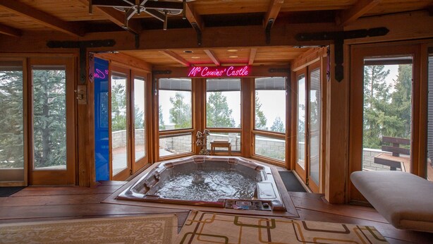 A hot tub in a wooden cabin with a neon sign reading "Mc Coyns' Castle".