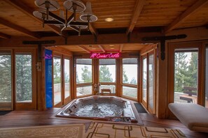 Un bain à remous dans un chalet en bois, avec un panneau lumineux au néon indiquant : « Le château des Mc Coyns ».