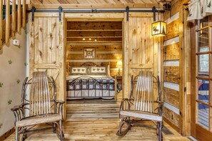 A rustic wooden room with a bed, two rocking chairs, and a wooden floor. - Screened in Porch- Hot Tub Table-Pet Friendly-Close to the Great Smoky Mountains (SEVIERVILLE)