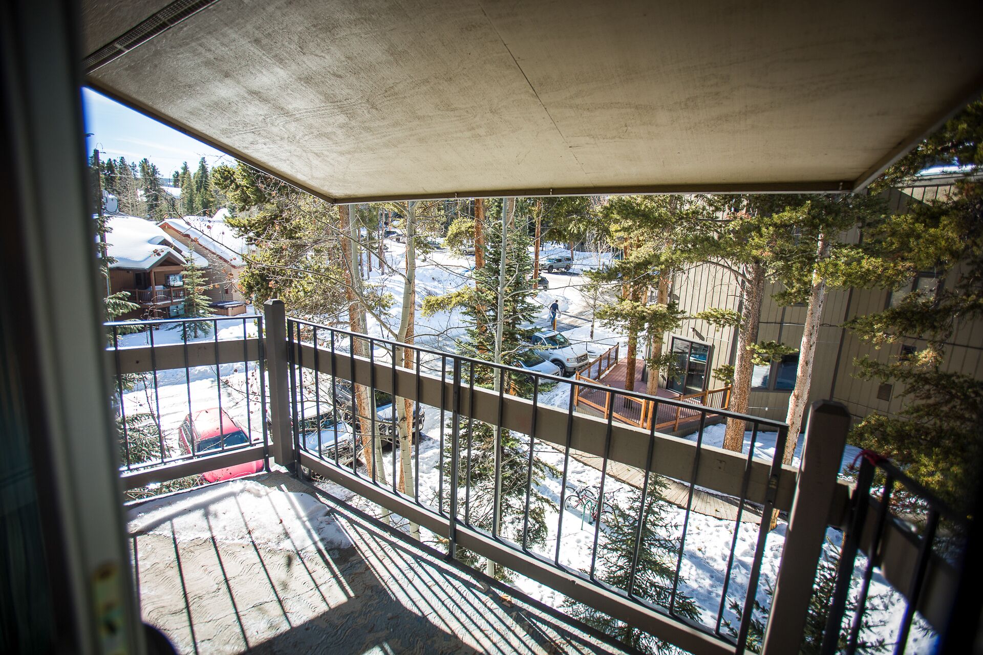 A balcony with a view of a snowy landscape, including trees and buildings.
