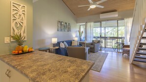 A spacious living area with a kitchen counter, a sofa set, a dining table, and a staircase leading to an upper level. - Resort Living Off the Beaten Path
AC , WIFI, and Fully Remodeled Bathroom (Kahuku)