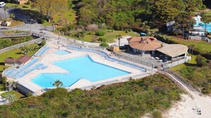 Vista aerea di un resort con una grande piscina, una spiaggia e un edificio con tetto.