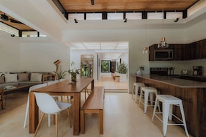 A modern kitchen with a wooden island, bar stools, and a dining area with a wooden table and chairs.