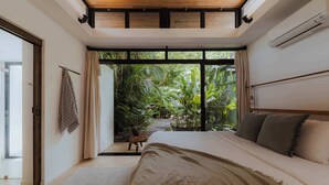 Un dormitorio con una cama grande, vistas a zonas verdes y una puerta corredera que da a un espacio exterior.
