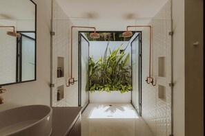 A modern bathroom with a freestanding bathtub, a large mirror, and a shower with copper fixtures.