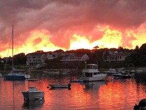 Un puerto deportivo con barcos amarrados, rodeado de casas y árboles bajo un cielo al atardecer.