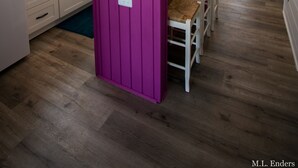 Una cocina con pisos de madera, una isla púrpura y un comedor con sillas y una mesa.