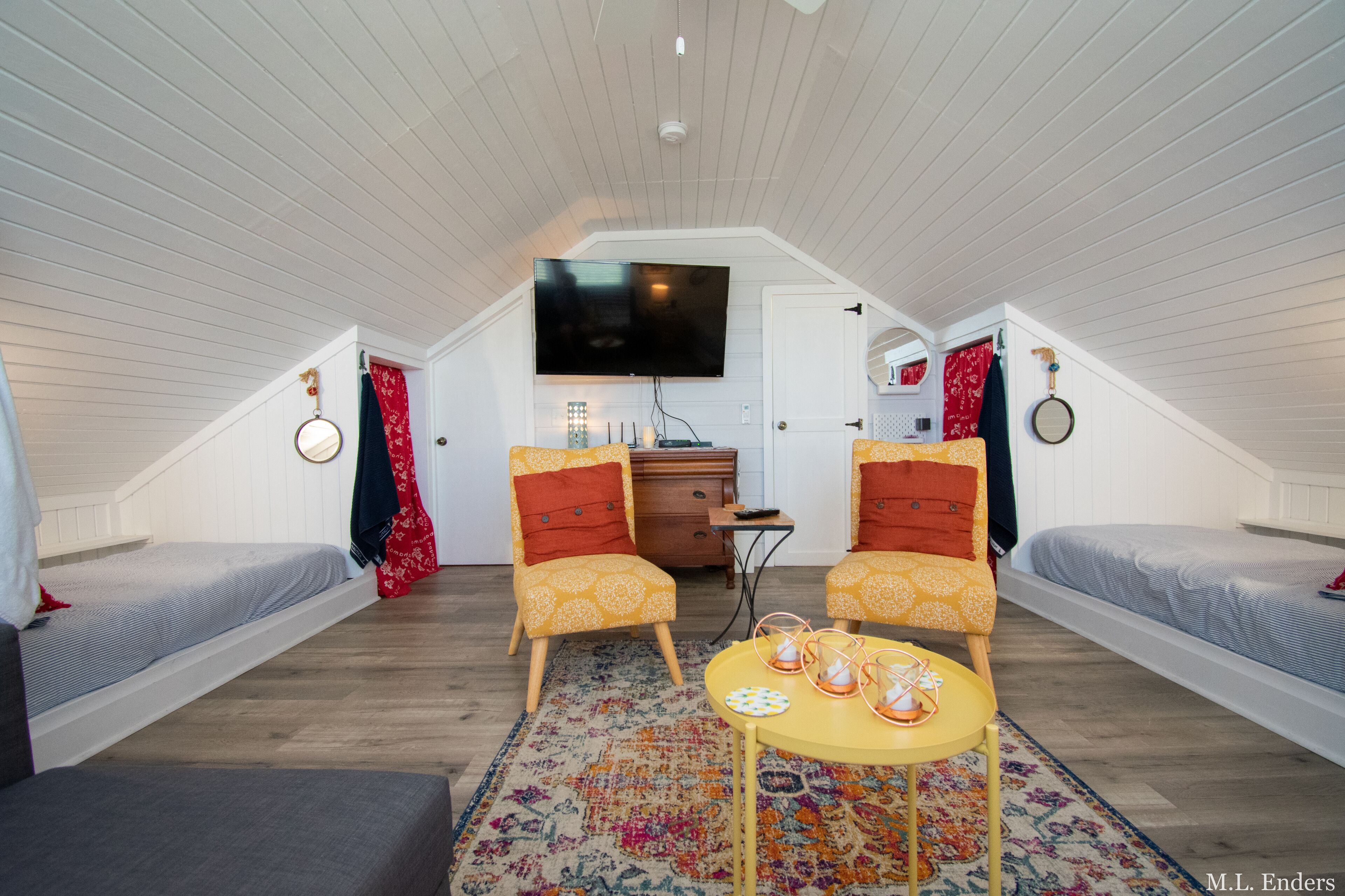 Ein gemütliches Schlafzimmer im Dachgeschoss mit zwei Einzelbetten, einem an der Wand befestigten Fernseher und einem kleinen Tisch mit Teppich.