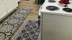 Une cuisine de taille réduite, avec des meubles blancs, une cuisinière et un coin repas comprenant une table et des chaises.