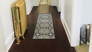 Un couloir avec un tapis à motifs, un radiateur et une porte au fond.