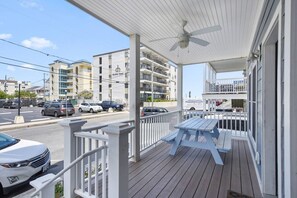 A covered porch with a ceiling fan, a table, and a railing.