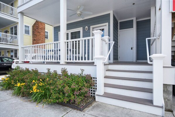 A two-story building with a porch, steps, and a brick chimney.