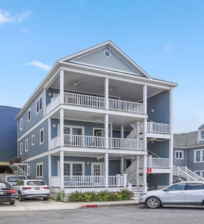 A multi-story building with balconies, a garage, and a parking area.
