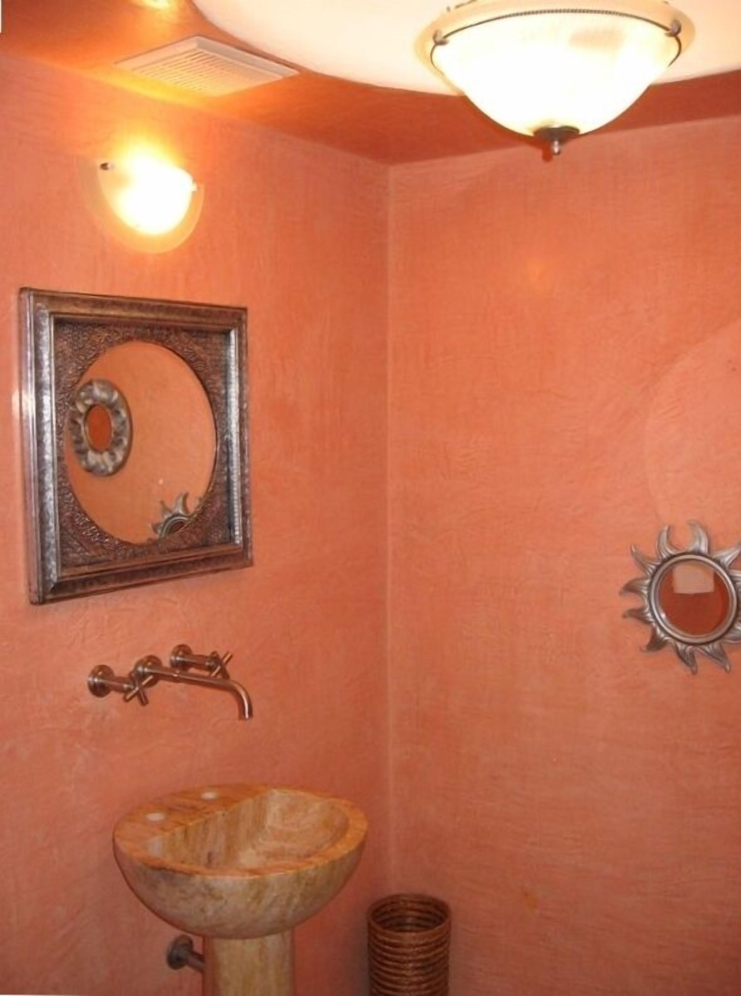 A bathroom with a wooden sink, a framed mirror, and a wall-mounted light fixture.