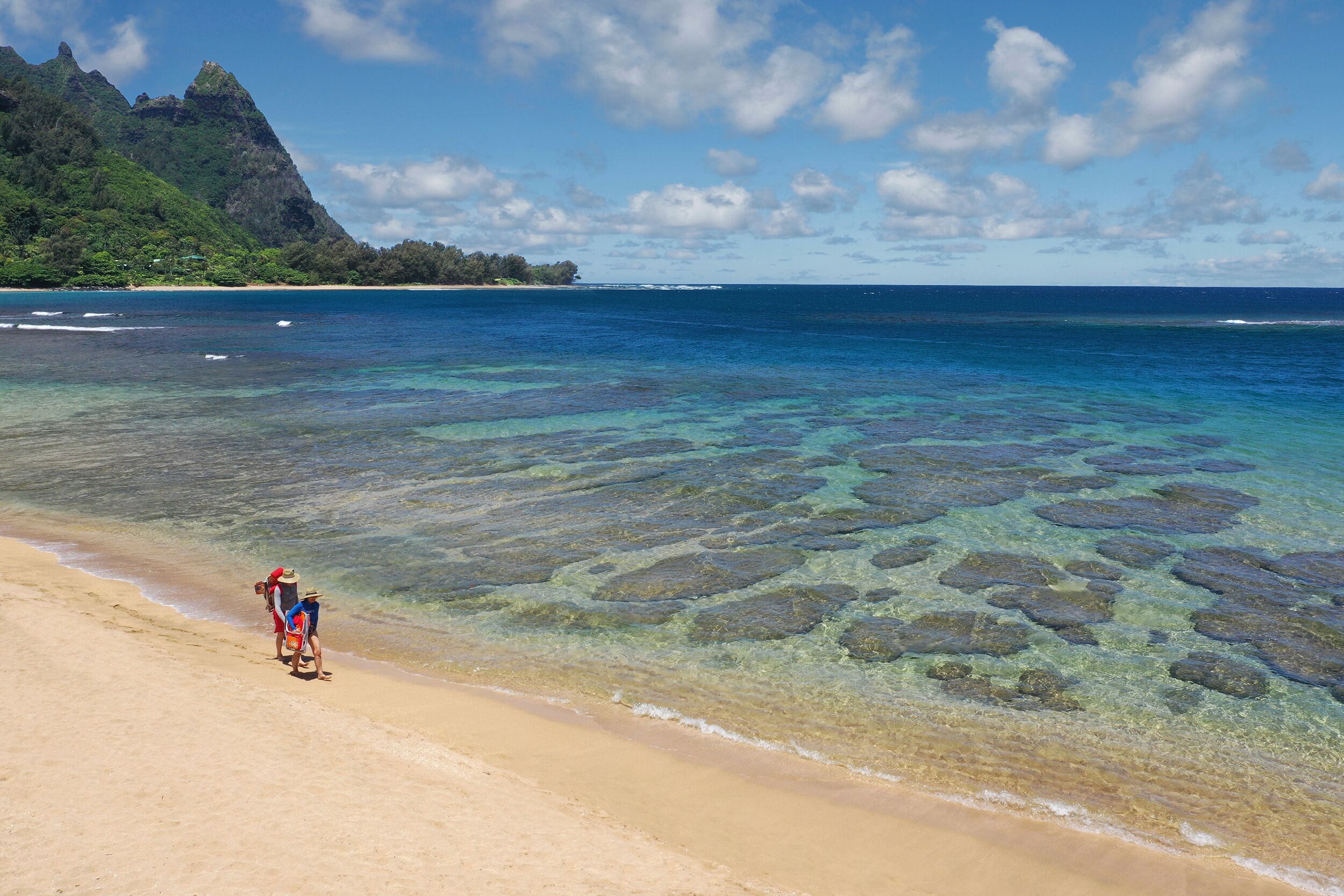 Una playa con aguas transparentes y poco profundas, y una montaña a lo lejos.