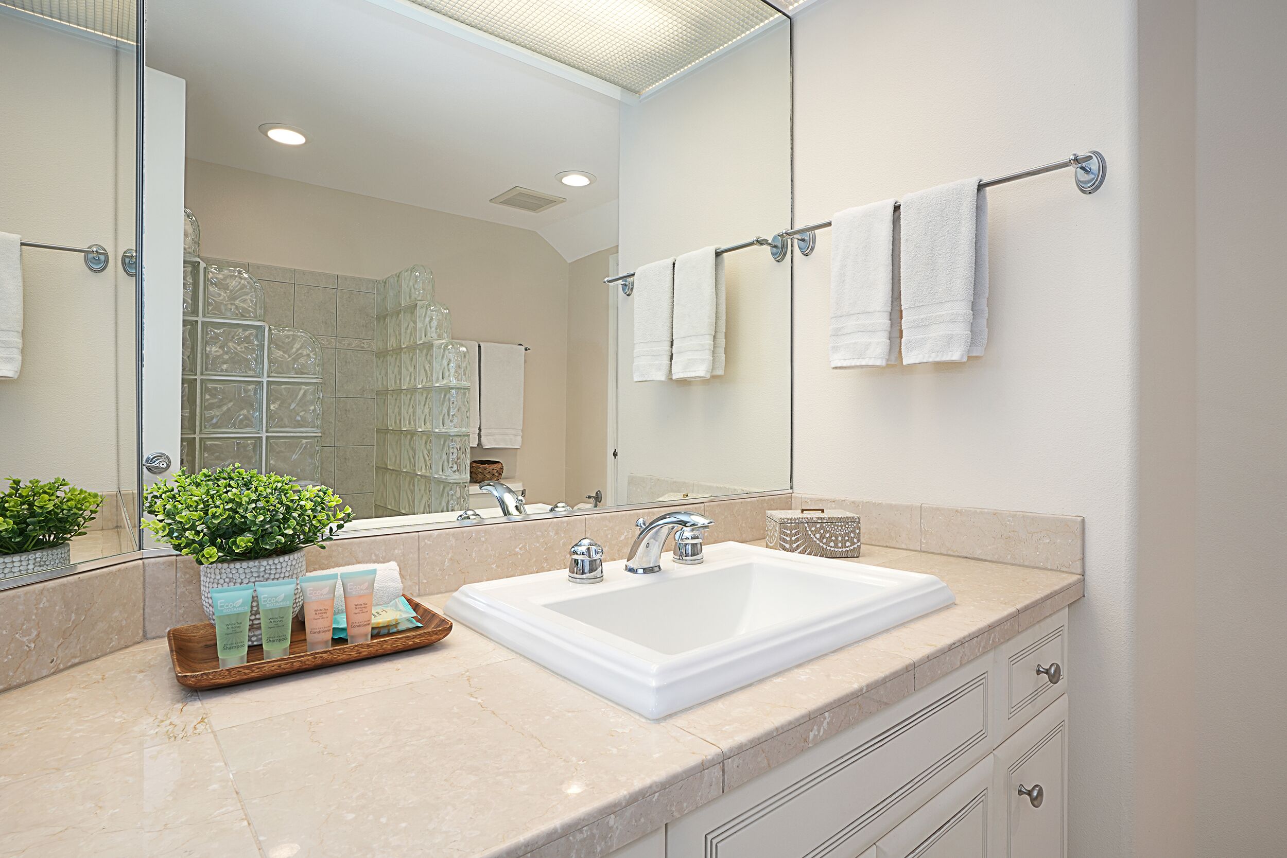 Un baño moderno con un espejo grande, un lavamanos blanco y un perchero para toallas.