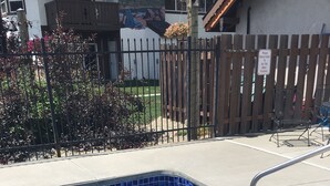A rectangular hot tub with blue mosaic tiles, surrounded by a wooden fence and a metal railing.