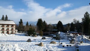 A snow-covered landscape with a building, rocks, and trees.
