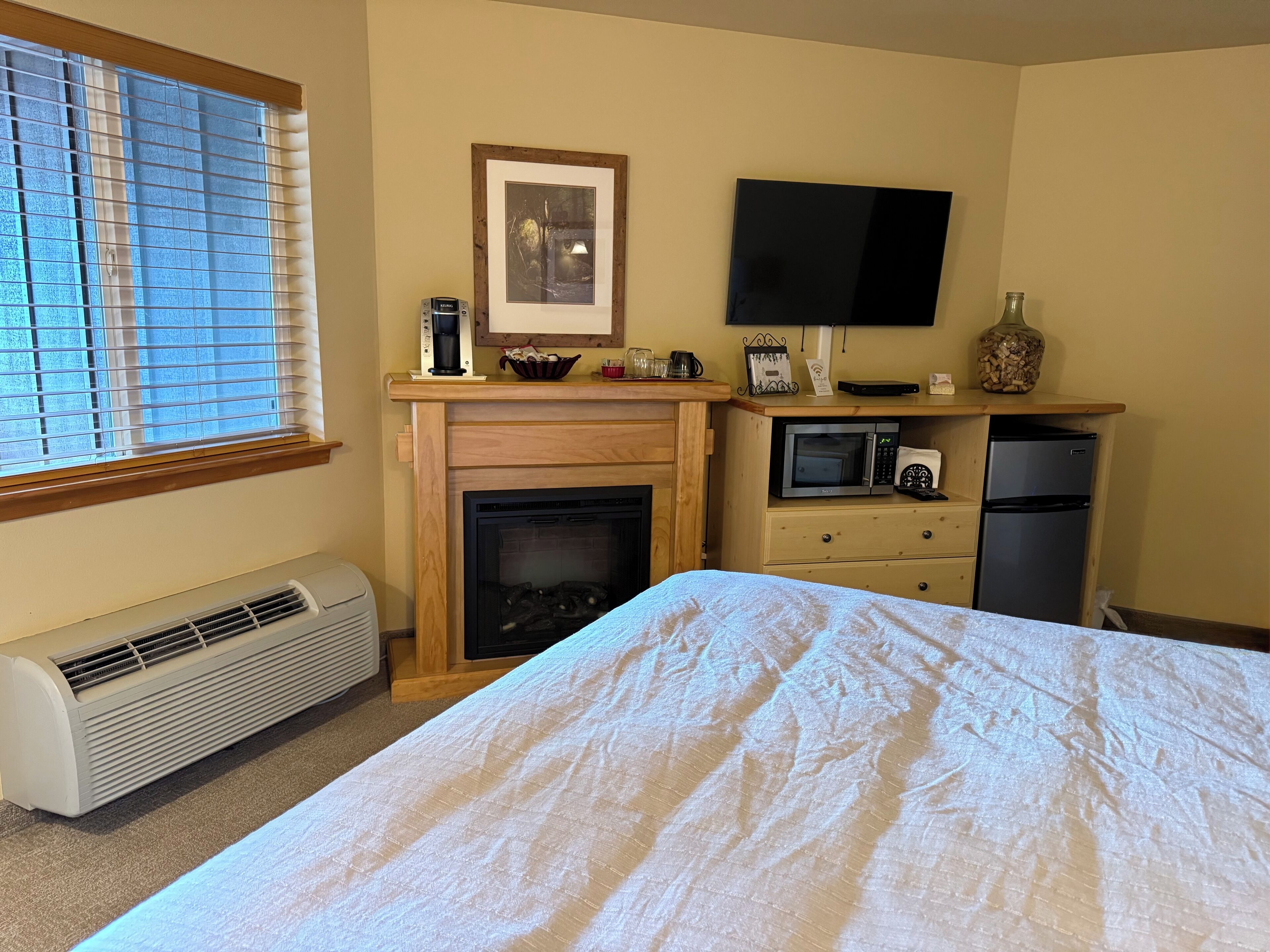 Quarto com cama, lareira, televisão, micro-ondas e frigorífico.
