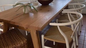 A dining area with a wooden table, white chairs, a bowl, and a potted plant. - Family Friendly Island Getaway (Nantucket)