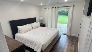 A bedroom with a bed, nightstands, a lamp, and a view of the outdoors. - Branson area Lakehouse, 5 Bedrooms, 3 Baths, (Sleeps 9-15) New decks Spring 2019 (Kimberling City)