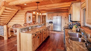 A log cabin interior with a central island kitchen, wooden floors, and a staircase. - Mountain Getaway w/additional Bunkhouse Apartment! (Anaconda)