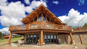 A log cabin with a balcony, stone walls, and large windows. - Mountain Getaway w/additional Bunkhouse Apartment! (Anaconda)