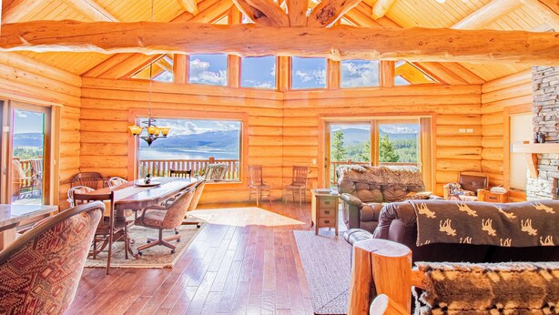 A log cabin interior with a dining area, seating, and large windows offering scenic views. - Mountain Getaway w/additional Bunkhouse Apartment! (Anaconda)