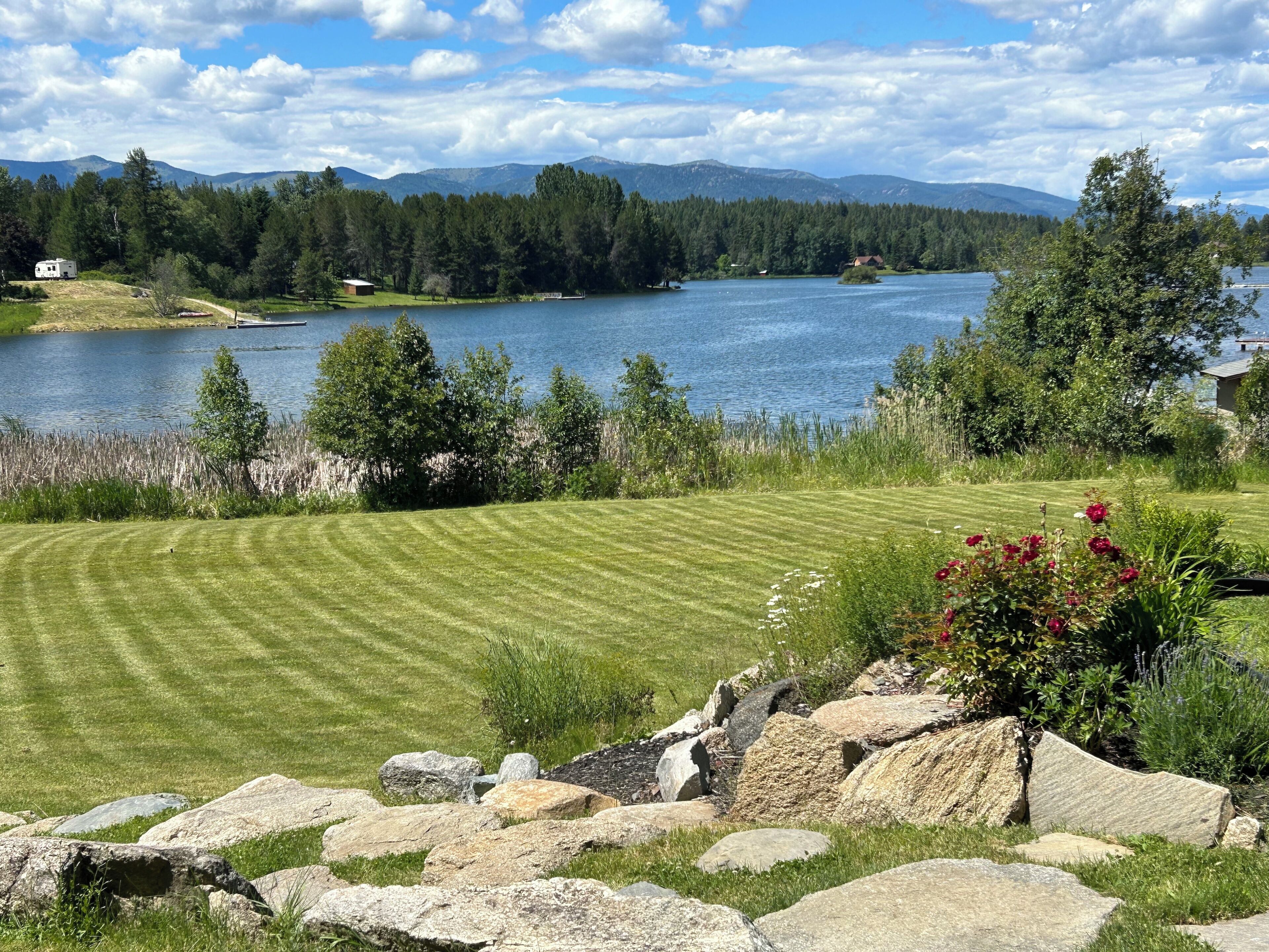 A lakeside property with a well-maintained lawn, a dock, and a cabin.
