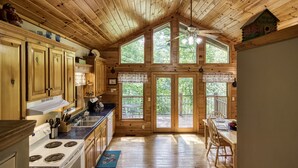 A wooden cabin kitchen with a large window, a dining area, and a ceiling fan. - Lake Front with Lake view, King size Bed Great Place to relax and go fishing (Sevierville)