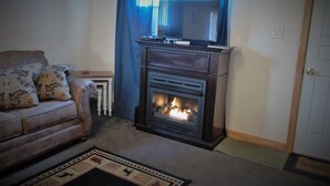 Una sala de estar con chimenea, un sofá y una televisión.