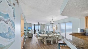 A spacious room with a dining area, kitchen, and a view of the ocean.