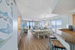 Um quarto espaçoso com área de jantar, cozinha e vista para o mar.