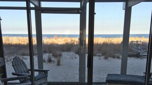Een overdekt terras met uitzicht op het strand, met twee stoelen en een bank.
