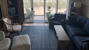 Een woonkamer met een grote schuifdeur die uitkomt op een terras met uitzicht op het strand.