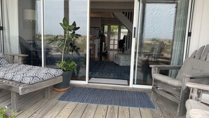 Een houten terras met een bank, een plant in pot en een vloerkleed.