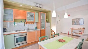 A modern kitchen with green cabinets, a marble countertop, and a dining area with a green tablecloth. - Lovely and Cheap Flat in the Central Area Appio -San Giovanni (rome)