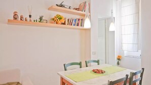 A dining area with a table, chairs, and shelves above. - Lovely and Cheap Flat in the Central Area Appio -San Giovanni (rome)